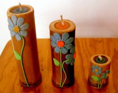 three wooden candles with painted flowers on them