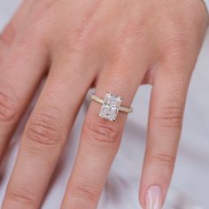 a woman's hand with a diamond ring on top of her finger and an engagement band