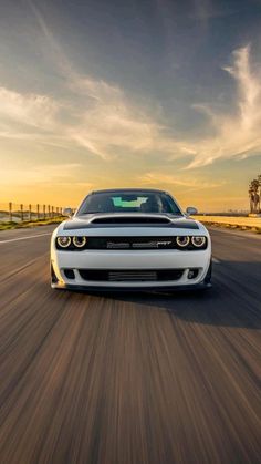 the front end of a white car driving down a road