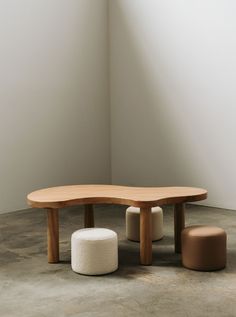 an oval wooden table with two stools next to it and a round ottoman on the floor