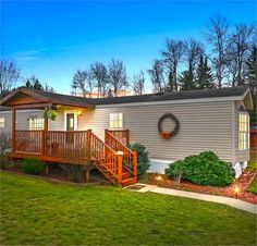 a mobile home with deck and stairs leading up to the front door at night time