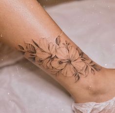 a close up of a person's foot with flowers tattooed on the side of her leg