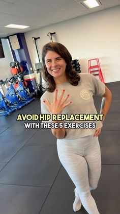 a woman with her hand up in the air while standing on a gym floor and smiling