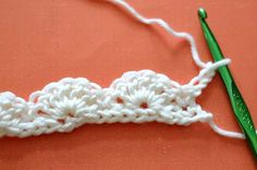 a crocheted piece of white yarn with a green knitting needle