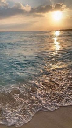 the sun is setting over the water at the beach