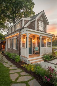 a small house with a porch and steps leading up to the front door is lit by lights