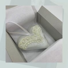 an open box with a white heart shaped pillow in it's lid and ribbon