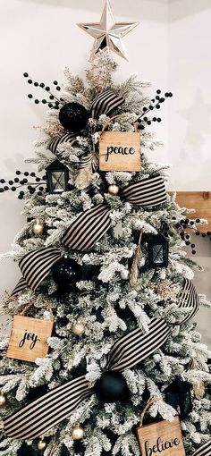 a christmas tree decorated with black and white ribbons, ornaments and wooden tags that say peace