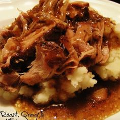 a white plate topped with mashed potatoes covered in gravy and pulled pork