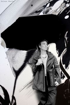 a man standing in front of a painting holding an umbrella