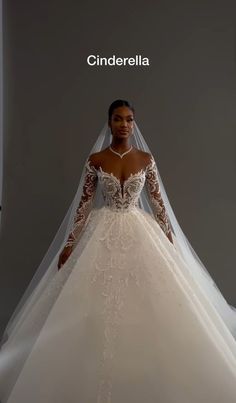 a woman wearing a wedding dress with long sleeves and a veil on her head, standing in front of a gray background