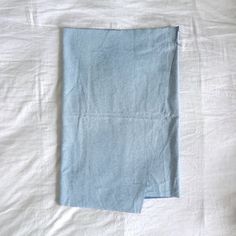 an unmade bed with white sheets and blue linens