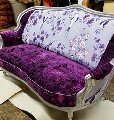 a purple and white couch sitting on top of a floor next to a pile of furniture