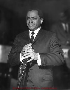 a black and white photo of a man in a suit holding an umbrella with his hands