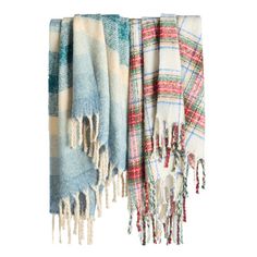 three different colored plaid blankets hanging on a white wall, one with fringes and the other with tassels