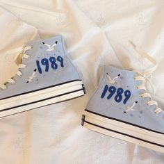 two blue sneakers with the word phi phi painted on them are laying on a white sheet