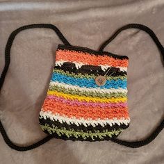 a multicolored crocheted purse sitting on top of a bed