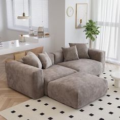 a living room with a large sectional couch in front of a window and a potted plant