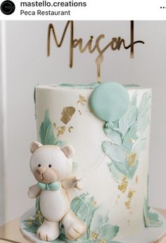 a white and green cake with a teddy bear on the top that says macaron