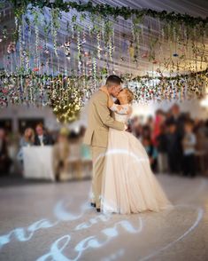 a bride and groom dance under a chandelier