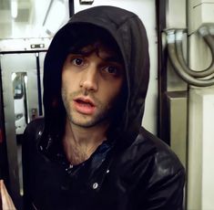 a man in a hoodie on a subway train looking at the camera and making a face