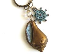 a keychain with a bronze shell and compass charm hanging from it's side