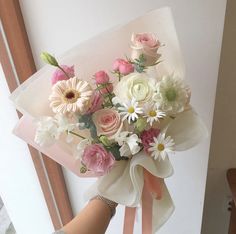 a woman holding a bouquet of flowers in her hand with pink and white roses on it