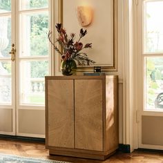 a vase with flowers on top of a wooden cabinet