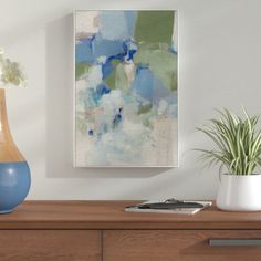 an abstract painting hangs on the wall above a dresser