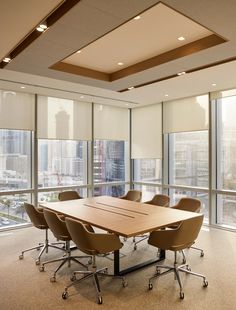 an empty conference room with chairs and a table in front of large windows overlooking the city