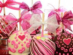 chocolate covered candies with pink bows and hearts on them sitting in front of candy sticks