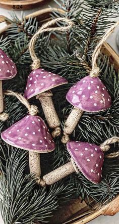 small purple mushrooms sitting on top of pine needles in a basket next to other decorations