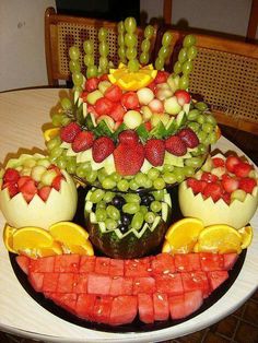 an arrangement of fruits arranged in the shape of a face on a white platter