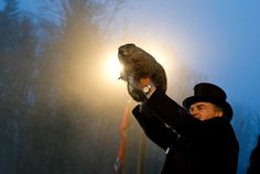 a man holding up a small animal on top of a pole in the snow at night