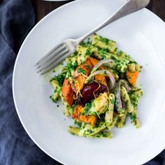 a white plate topped with pasta and veggies next to a bowl of broccoli