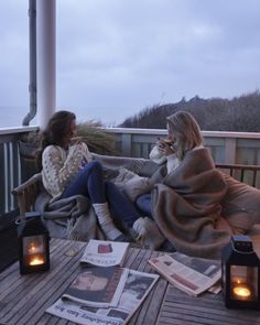 two women sitting on a porch with newspaper and candles