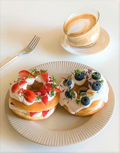 two donuts on a plate next to a cup of coffee