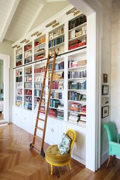 a ladder leaning up against a bookcase in a room with white walls and wooden floors