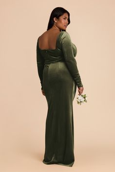 a woman in a long green dress holding a flower and looking off to the side