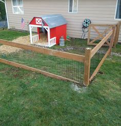 a red barn with a white roof is next to a wooden fence and green grass