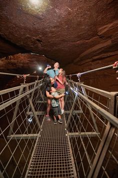 three people standing on a metal walkway in a cave