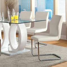 a glass dining table with white chairs around it