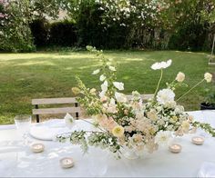 a table with flowers and candles on it in the middle of a backyard area,