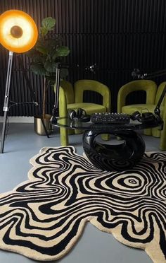 a black and white area rug on the floor in front of two green chairs with yellow lights