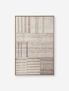 a beige and grey rug hanging on a wall next to a wooden framed artwork piece