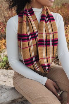 a woman sitting on a rock wearing a scarf