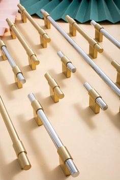 several different types of metal handles on a table with folded paper fans in the background