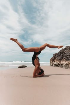 a woman doing a handstand on the beach