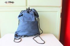 a denim bag sitting on top of a white table next to a red door and drawers