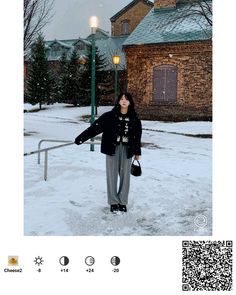 a woman standing in the snow next to a street light